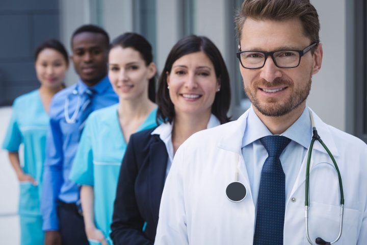 Portrait of smiling doctors standing in row at hospital premises